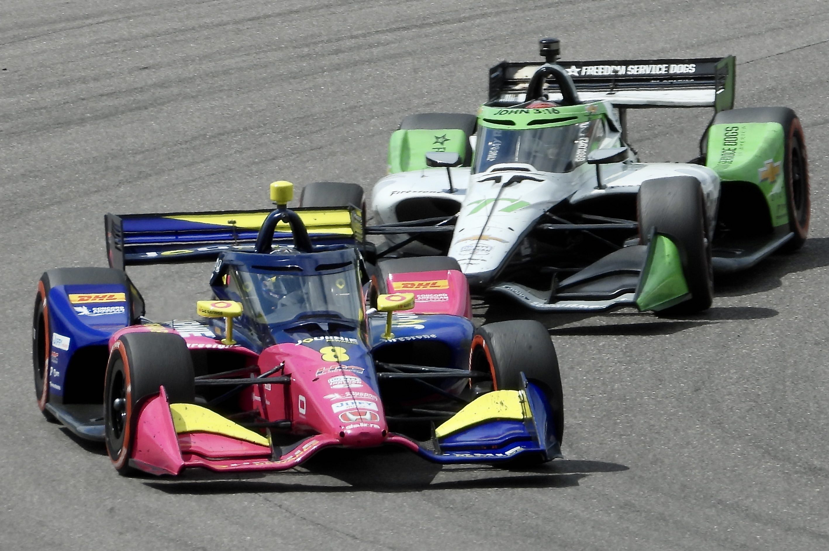 Two Indy cars wheel to wheel moving from left to right